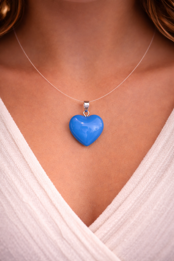 Blue heart-shaped pendant on a necklace against a white shirt background
