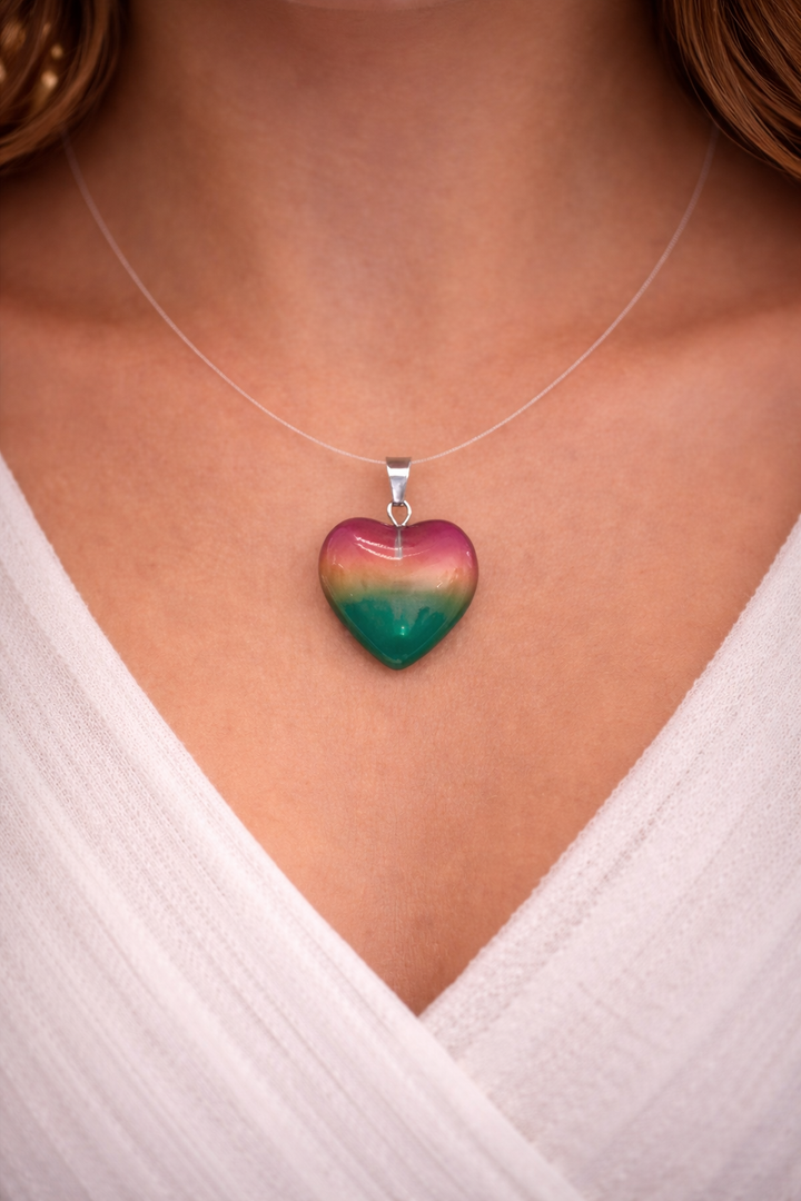 Heart-shaped pendant necklace with a gradient design on a person wearing a white top.