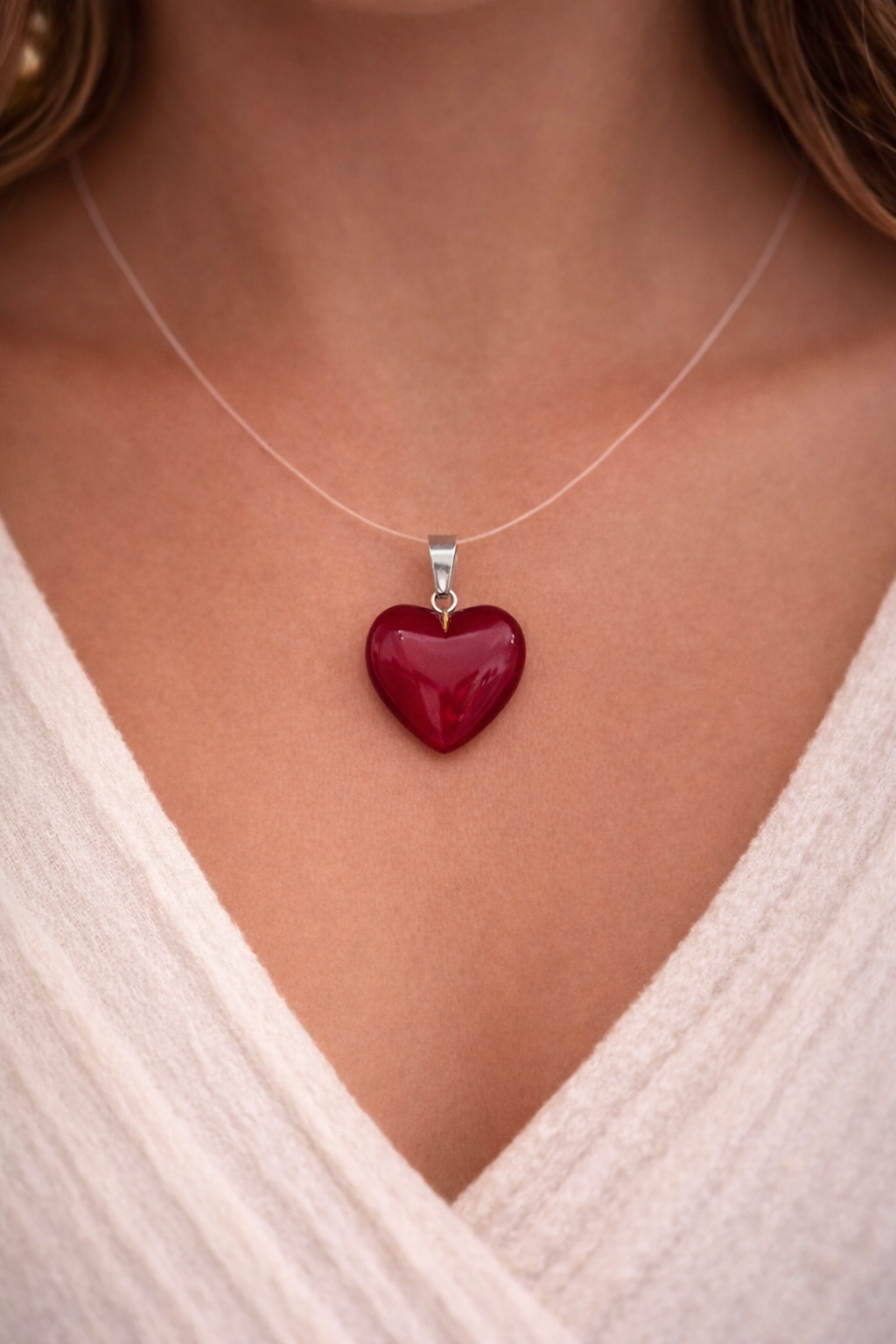 Red heart-shaped pendant on a necklace against a neutral background