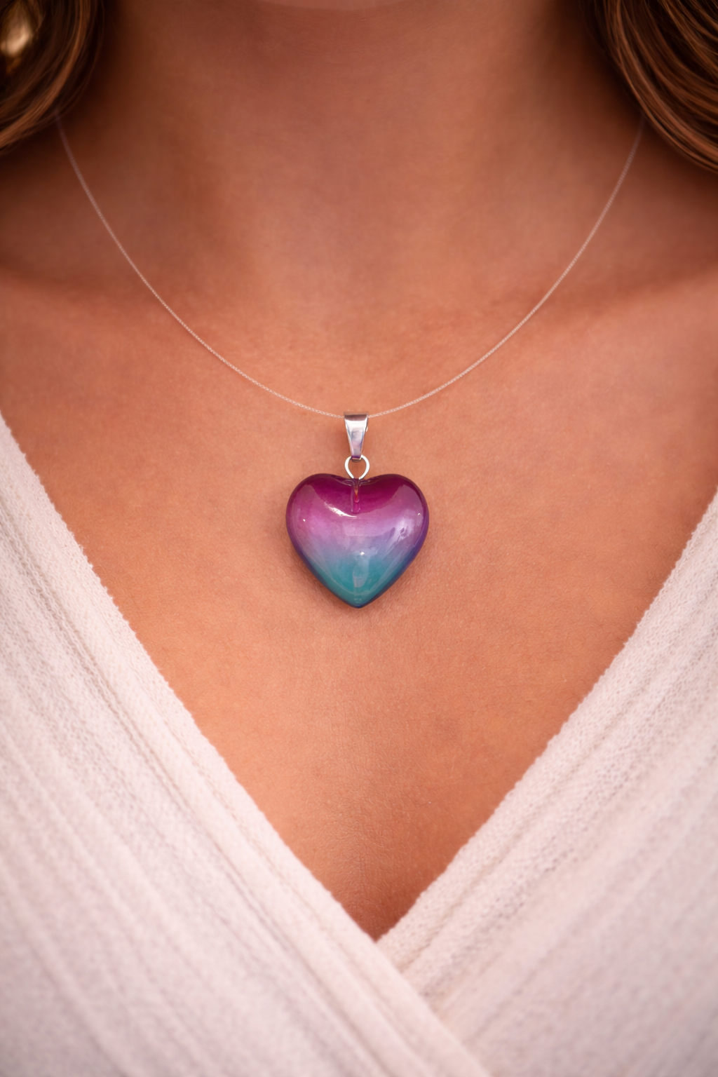Heart-shaped pendant necklace on a person wearing a white top