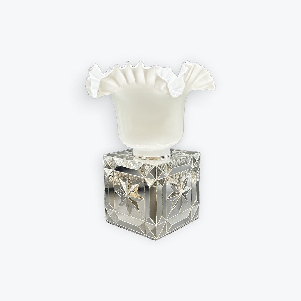 A vintage-style perfume bottle featuring a faceted, star-cut clear glass base and a white ruffled glass neck, set against a plain light gray background.