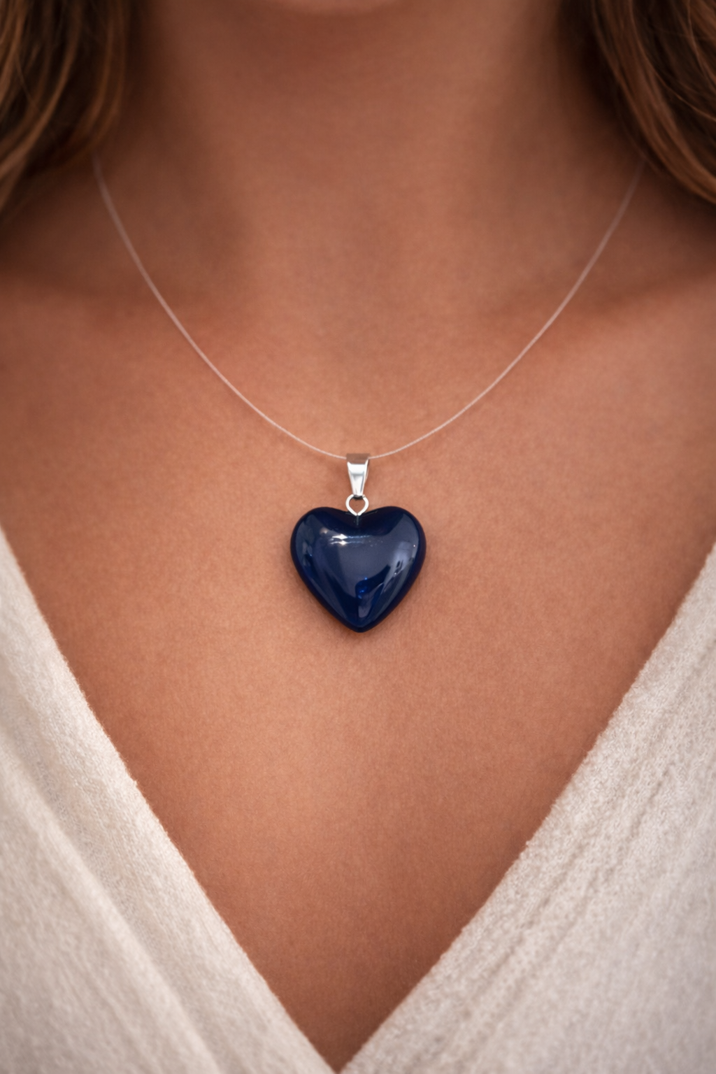 Blue heart-shaped pendant on a necklace against a neutral background