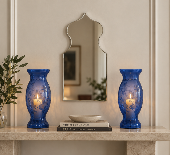 Pair of blue glass Mardangi candle holders styled with a decorative mirror on a minimalist console.