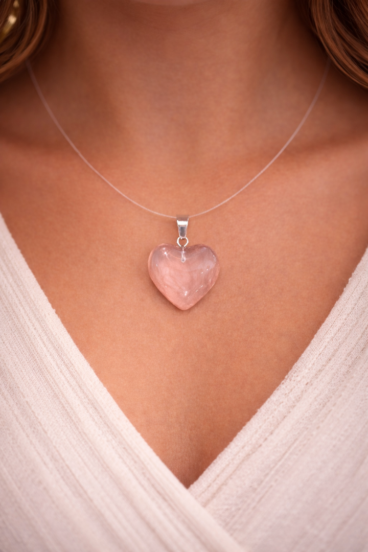 Heart-shaped pink pendant necklace on a person wearing a white top