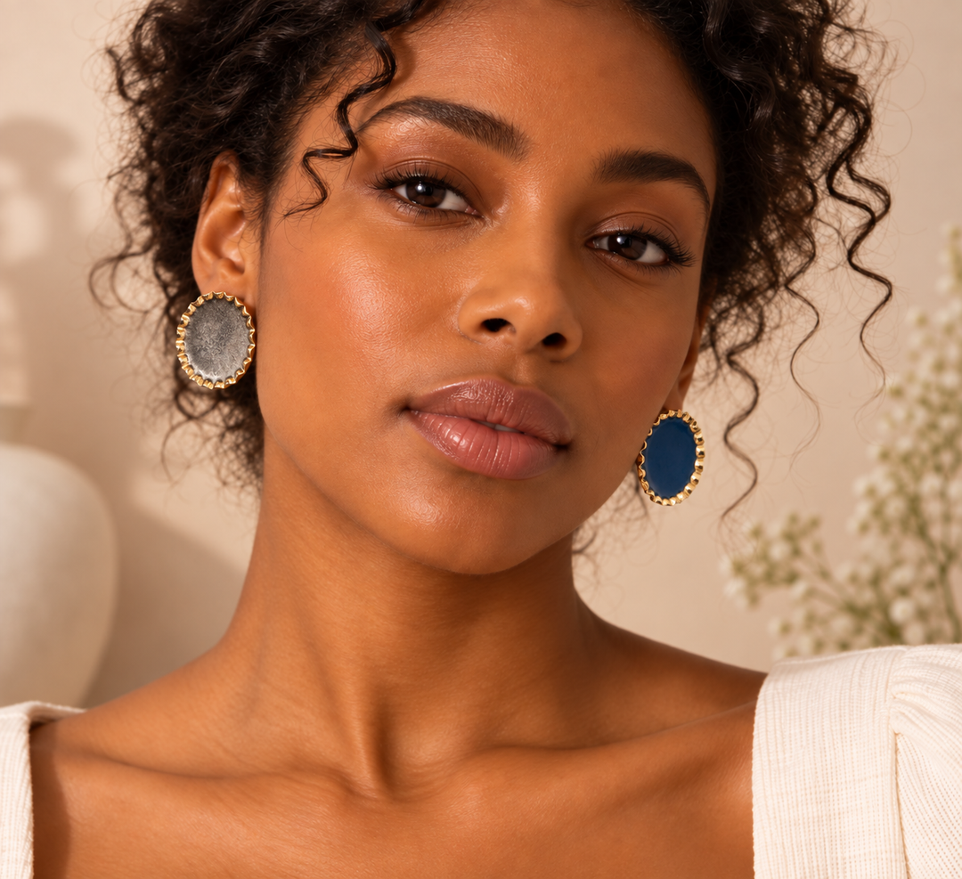Handmade mismatched round statement earrings with blue and silver centers and gold-toned textured edges, shown on a model