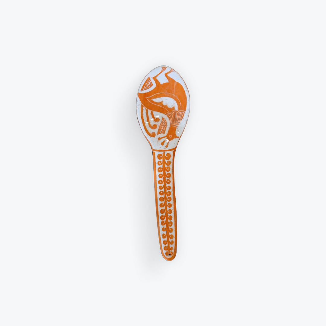 A small decorative spoon with an orange and white abstract pattern, shown against a plain white background.