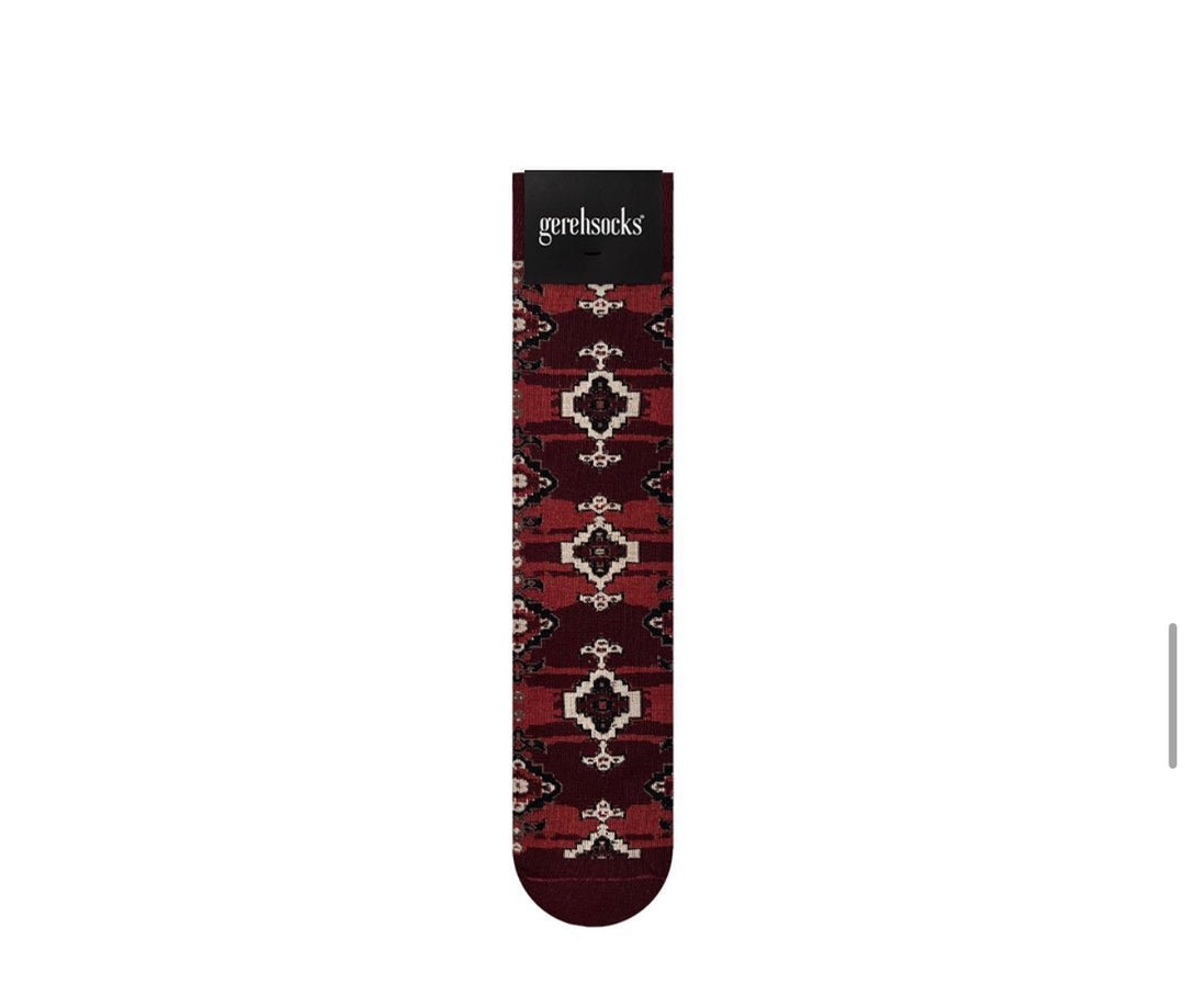 A single Gehrsocks sock with a dark red and black geometric pattern and cream accents, shown vertically on a plain white background.