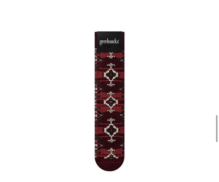 A single Gehrsocks sock with a dark red and black geometric pattern and cream accents, shown vertically on a plain white background.