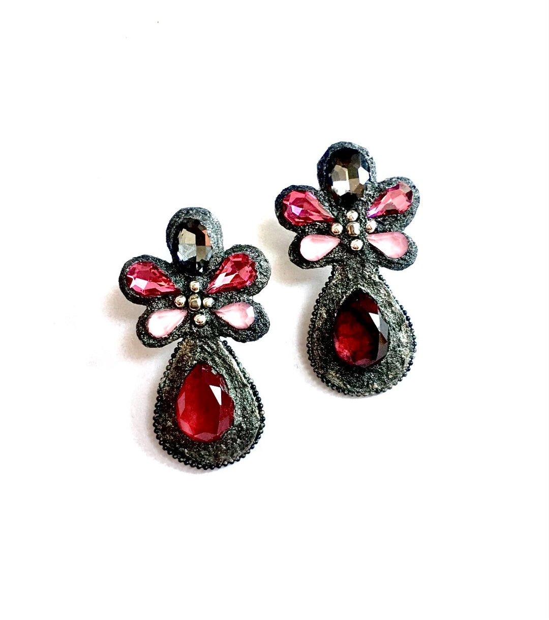 A pair of gothic-style black brooches decorated with faceted dark red teardrop crystals, pink and clear rhinestones, and small silver beads, set against a plain white background.