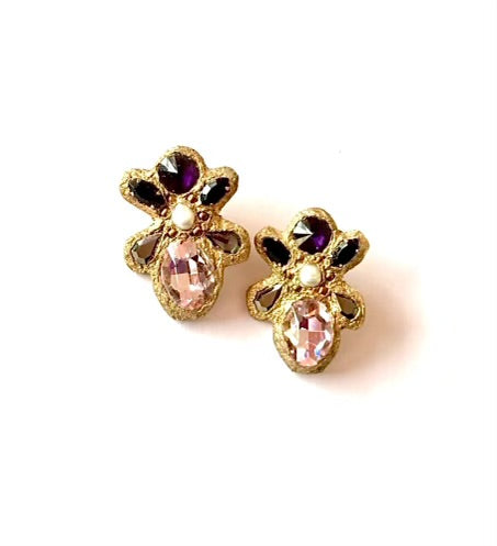 A pair of vintage-style gold-tone stud earrings shaped like flowers or butterflies, featuring faceted pink teardrop crystals, small black oval stones, and a central white pearl-like accent, set against a plain white background.