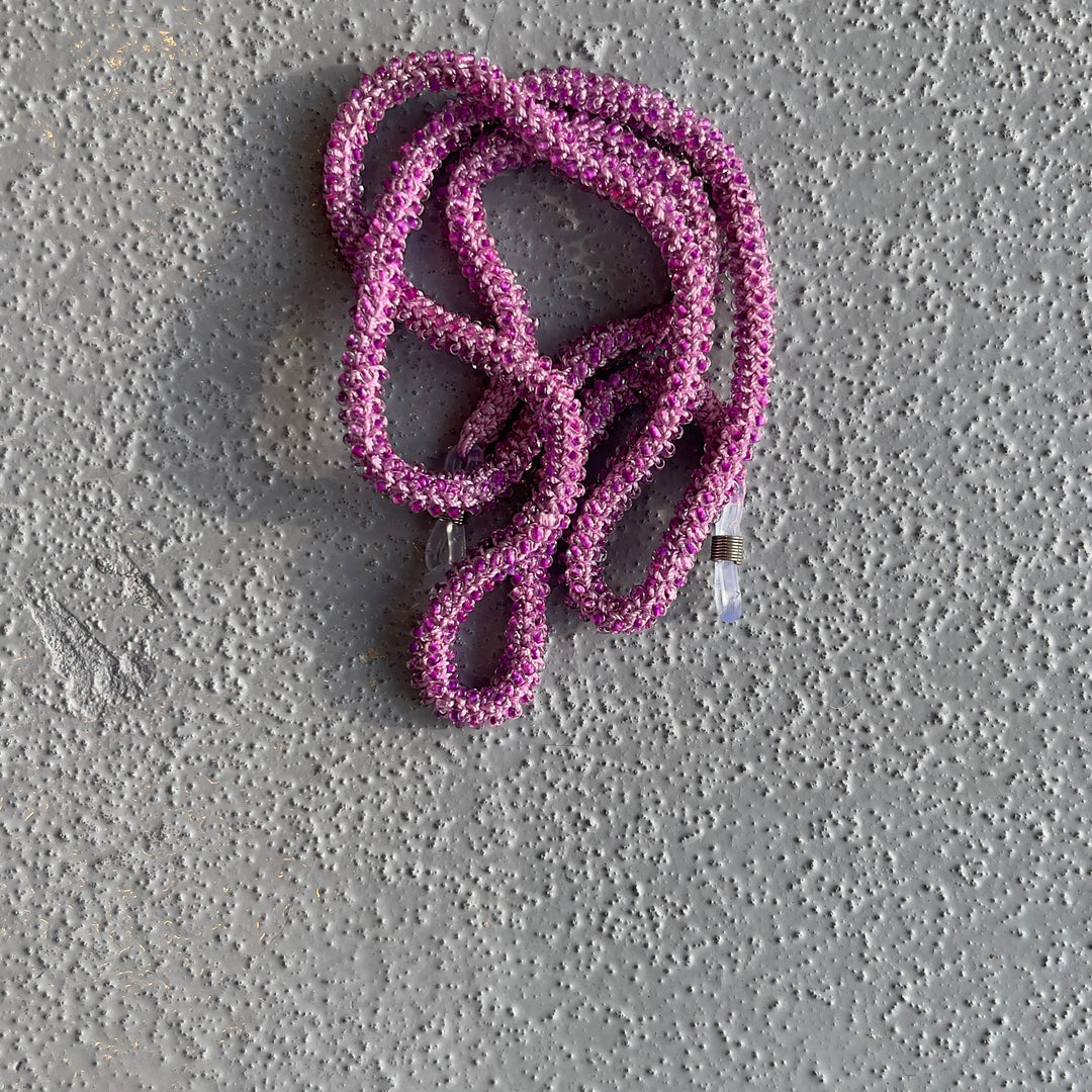 A coiled pink rope or cord lies on a textured gray concrete surface.