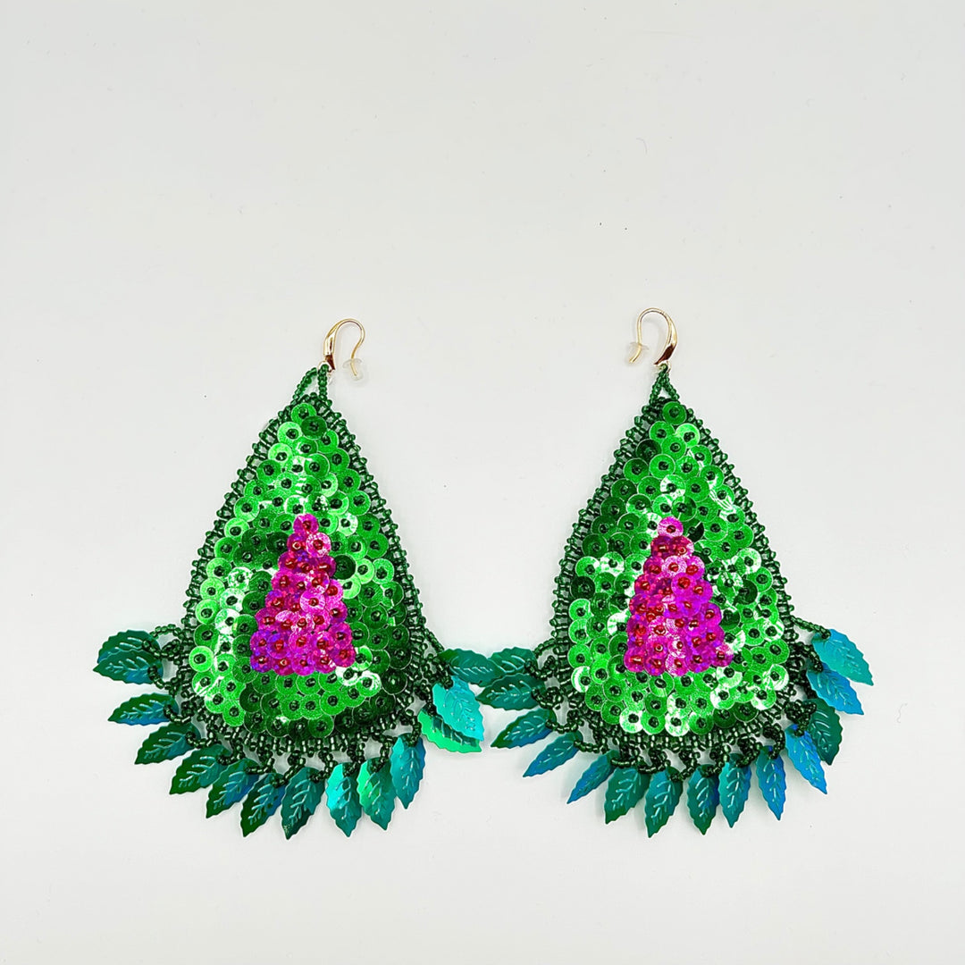 A pair of handmade teardrop-shaped dangle earrings decorated with green sequins, a bright pink sequined center, and teal-blue leaf-like fringe, shown on a plain light background.