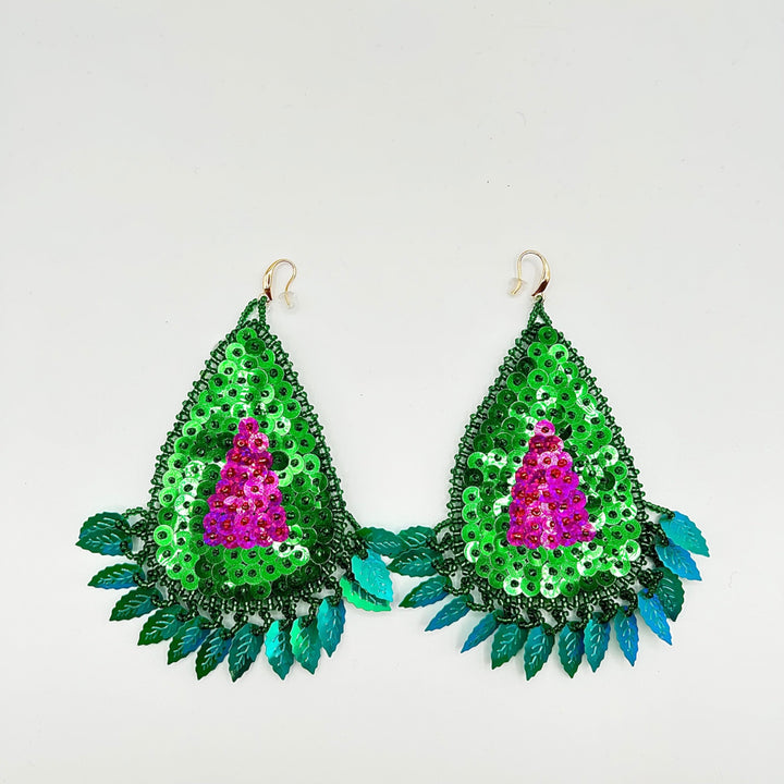 A pair of handmade teardrop-shaped dangle earrings decorated with green sequins, a bright pink sequined center, and teal-blue leaf-like fringe, shown on a plain light background.