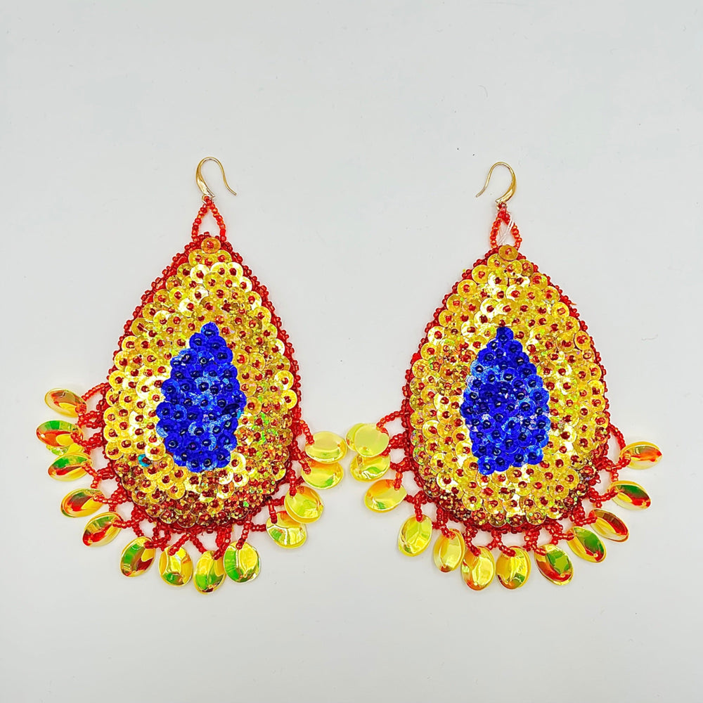 A pair of large, ornate teardrop-shaped dangle earrings decorated with yellow sequins, a central royal blue sequin motif, and red beaded borders with dangling multicolored faceted beads on a light gray background.
