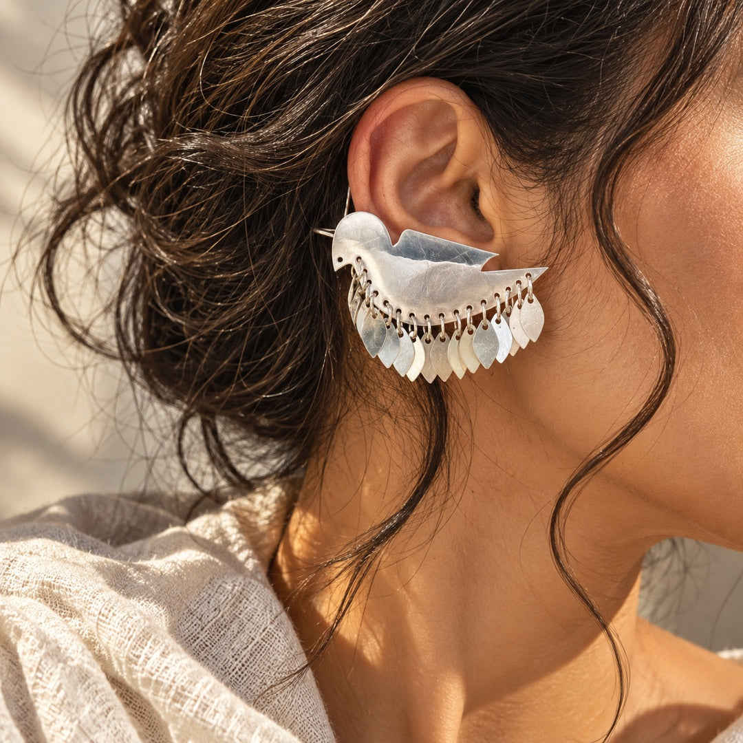 Silver bird statement ear cuff earring with dangling leaf details worn on a model
