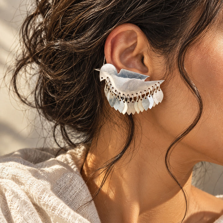 Silver bird statement ear cuff earring with dangling leaf details worn on a model
