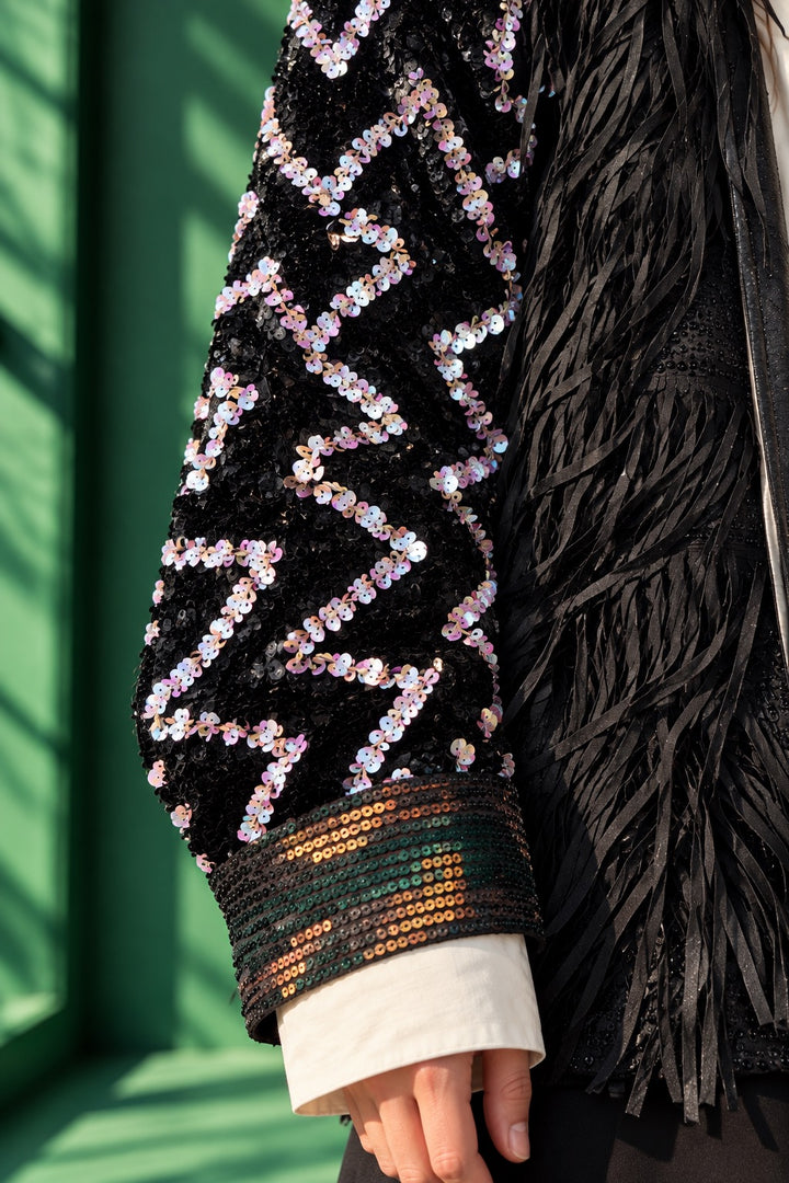 Close-up of the Zig Zag handcrafted black jacket by artist Ladan, featuring intricate hand-sewn iridescent sequins, textured fringe and embellished cuffs.