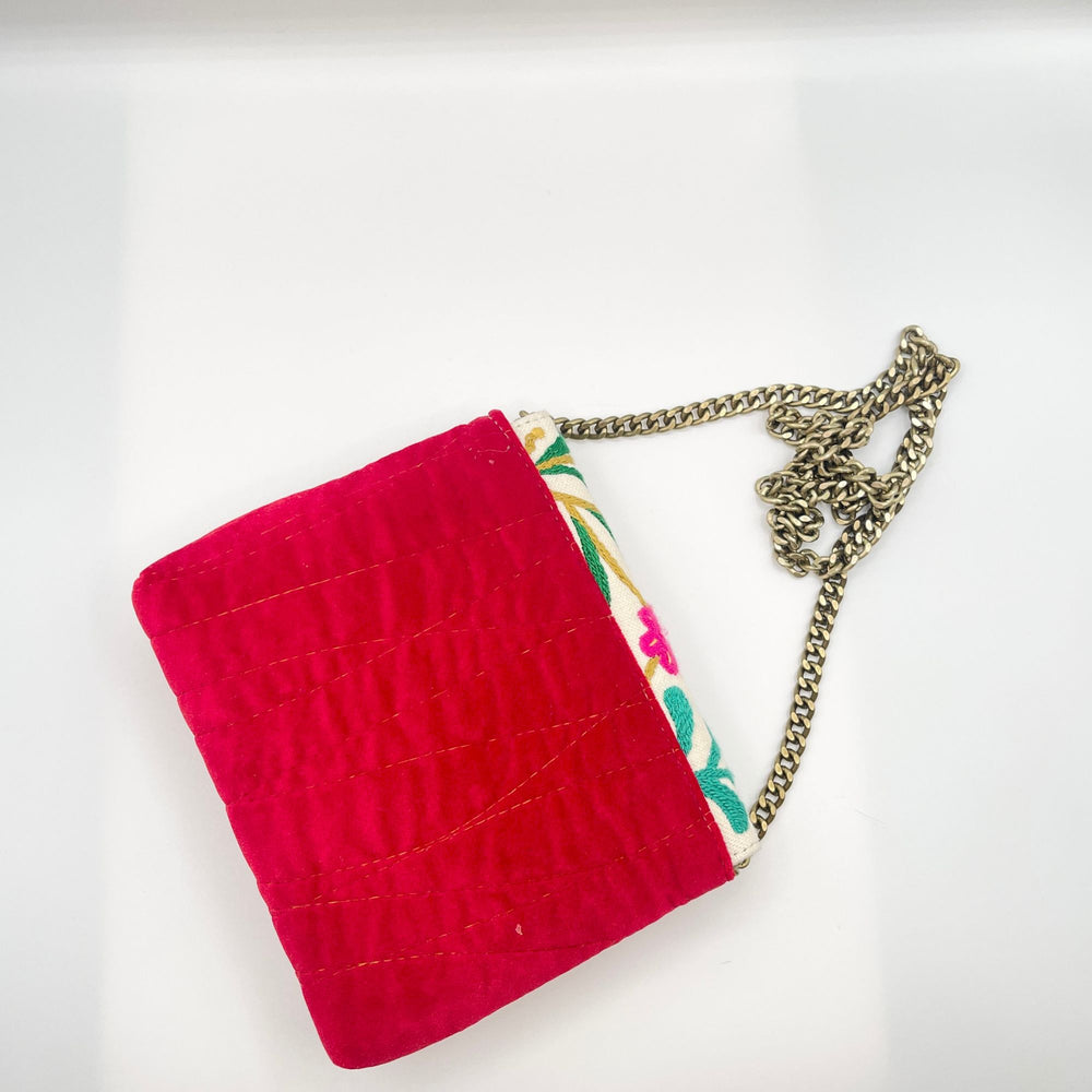Red clutch bag with a floral patterned strap on a white background